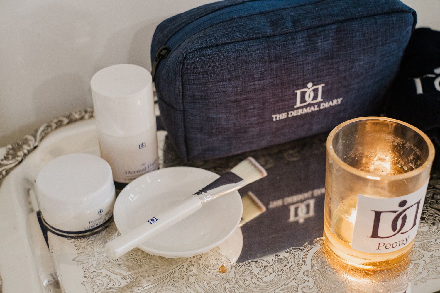 Luxury candles and home fragrances arranged on white marble surface with elegant packaging and warm lighting.