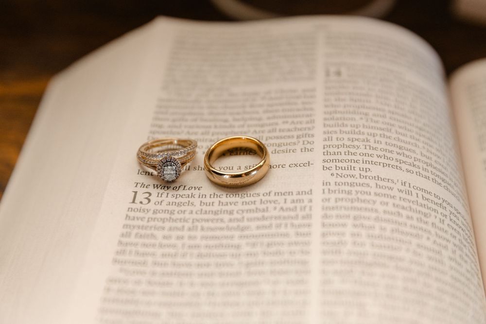 Two wedding rings rest on an open book page with text visible beneath them.