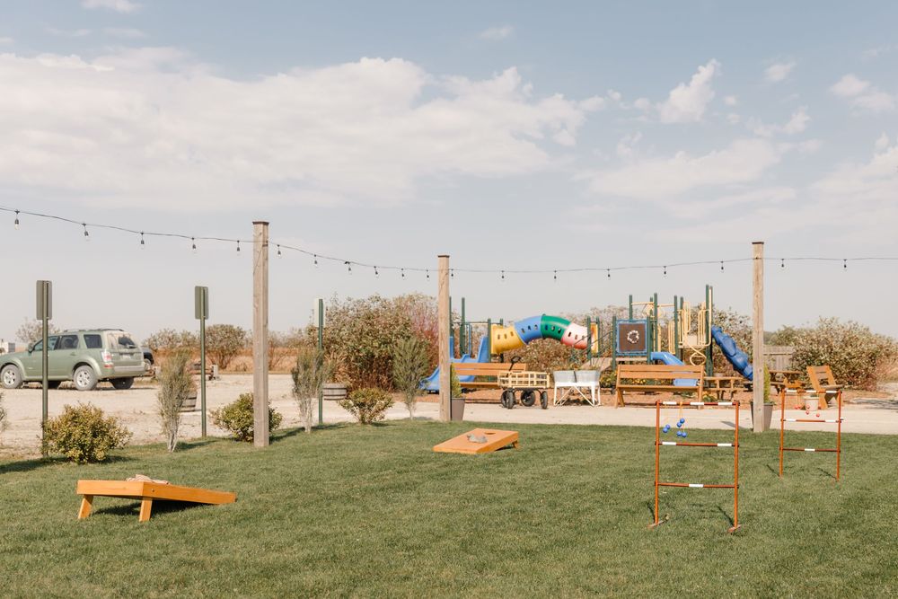 String lights illuminate an outdoor event space with rustic wooden benches and decorations set against a natural landscape.