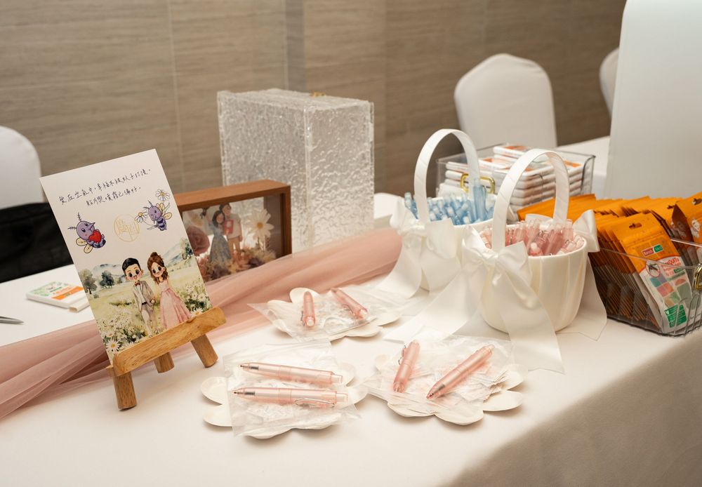 Delicate pink and white party decorations arranged on a white surface with floral accents and ribbons.