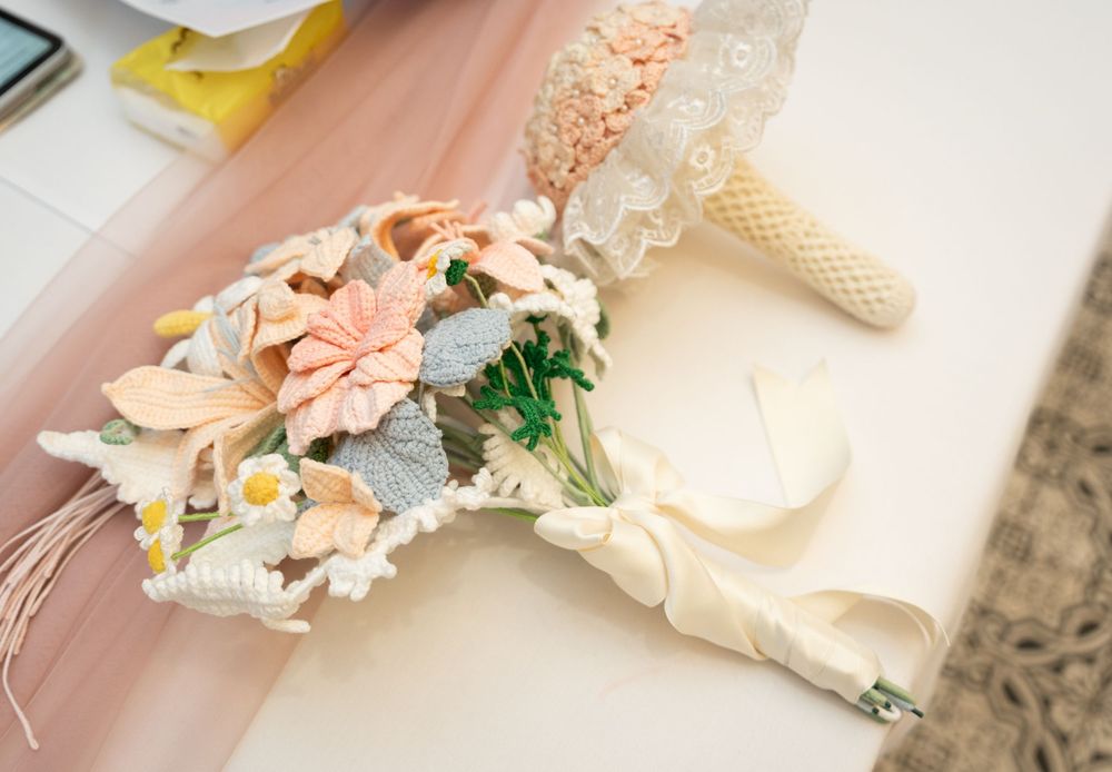 Soft pink and cream colored party favors and decorative elements laid out in a row on white surface.