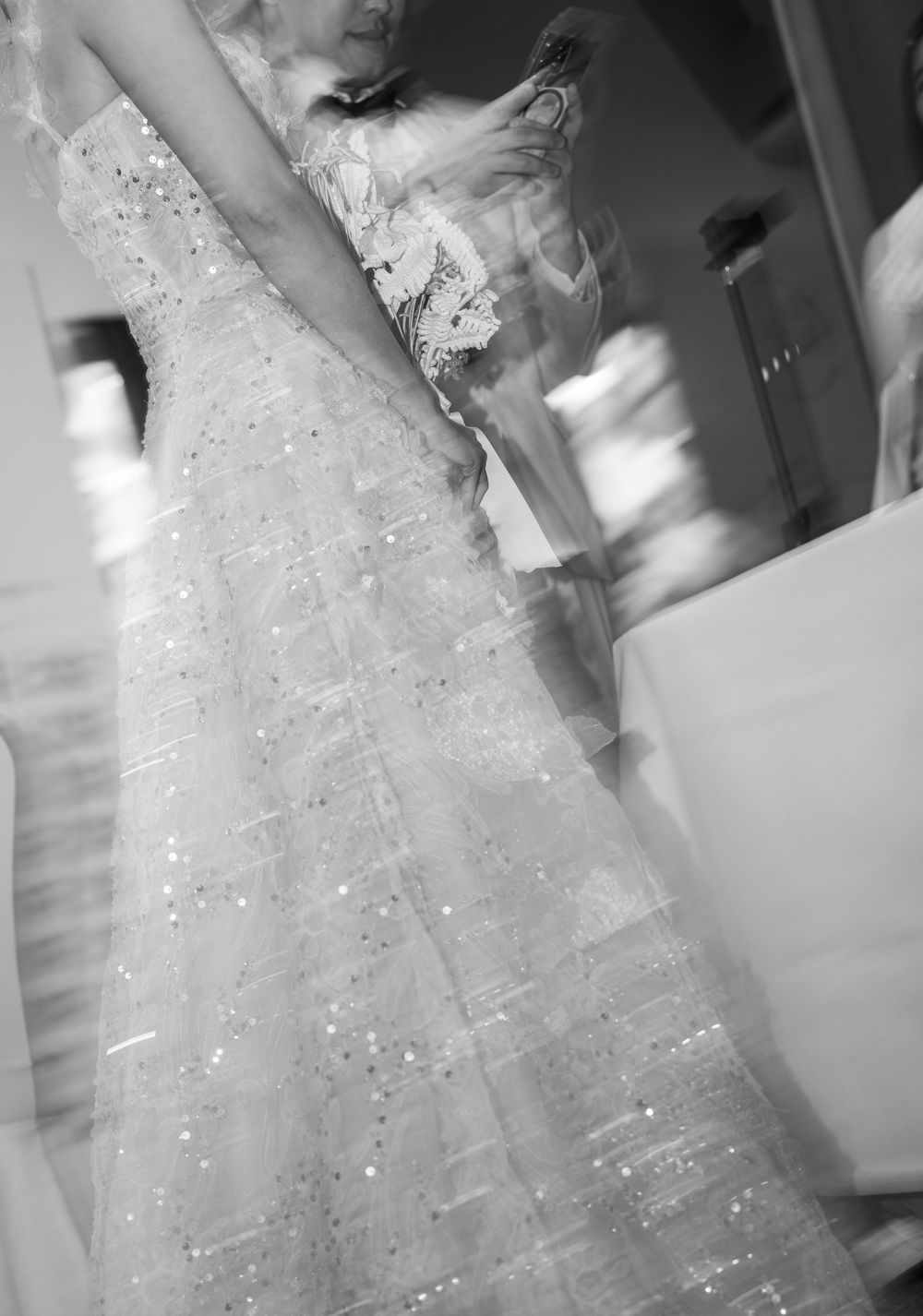 A close-up view of a sparkling white wedding dress with intricate beadwork and delicate lace details.