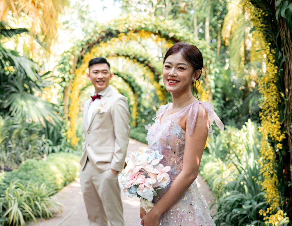 A couple in wedding attire share joyful moments together in a lush tropical garden setting during their photoshoot.