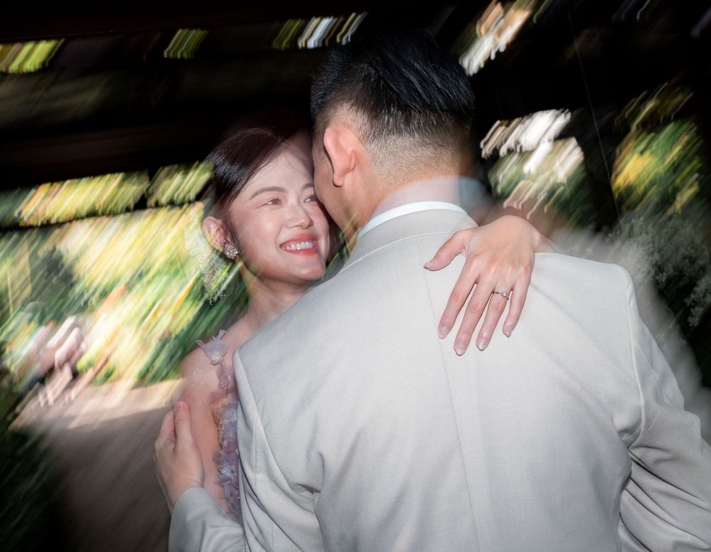 A couple embraces during a dance at an outdoor wedding reception with motion blur effects in the background.