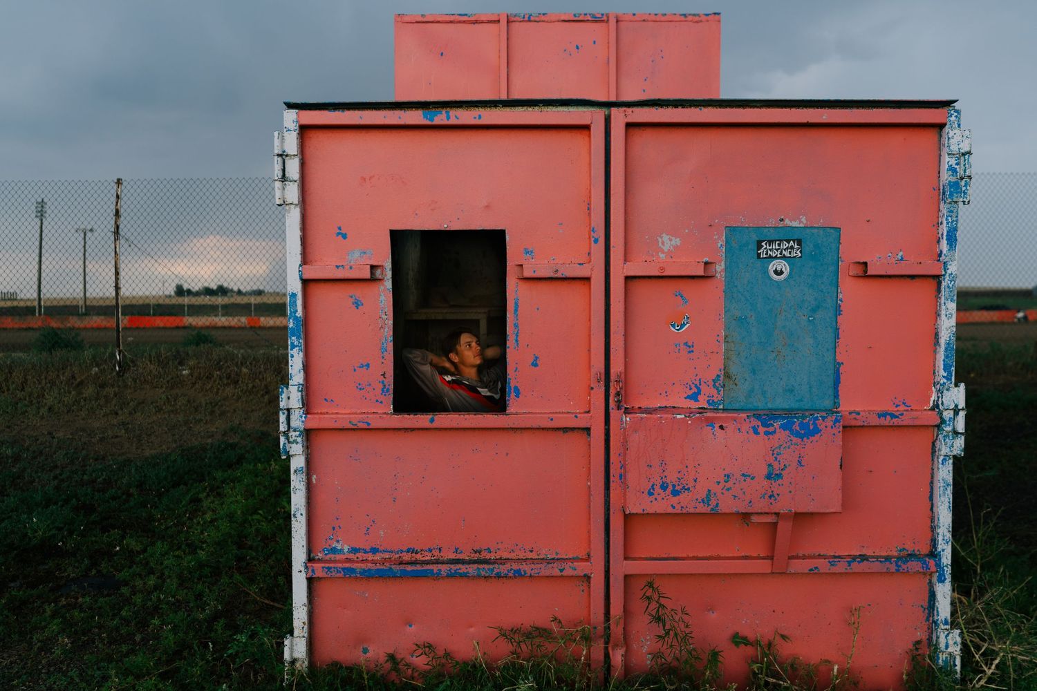 A row of pink-colored storage containers or sheds lined up against a cloudy sky.