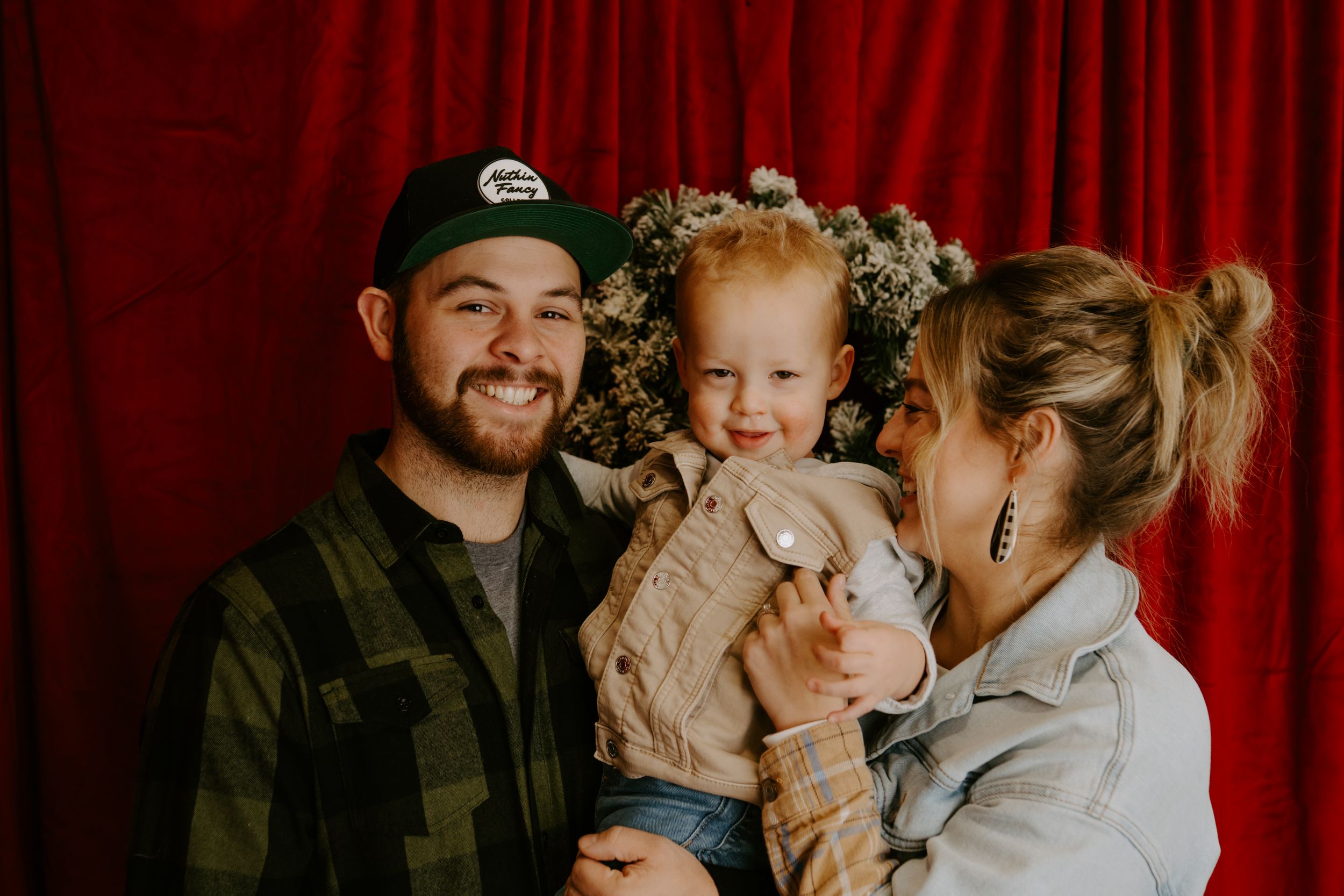 Family portrait session with red curtain background and floral decorations.
