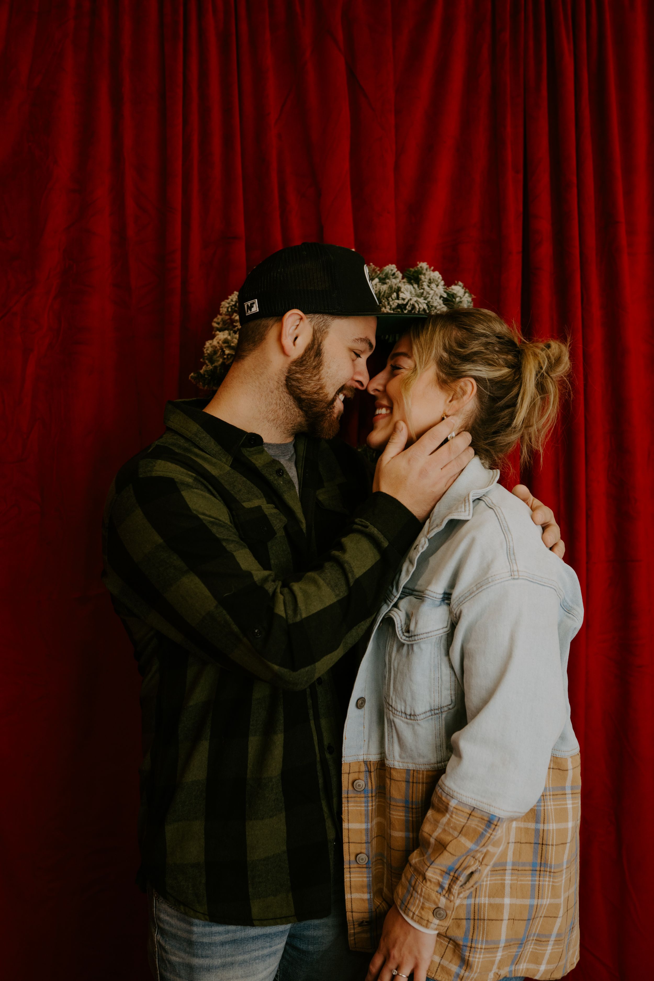 Intimate couple embracing against dramatic red curtain backdrop.