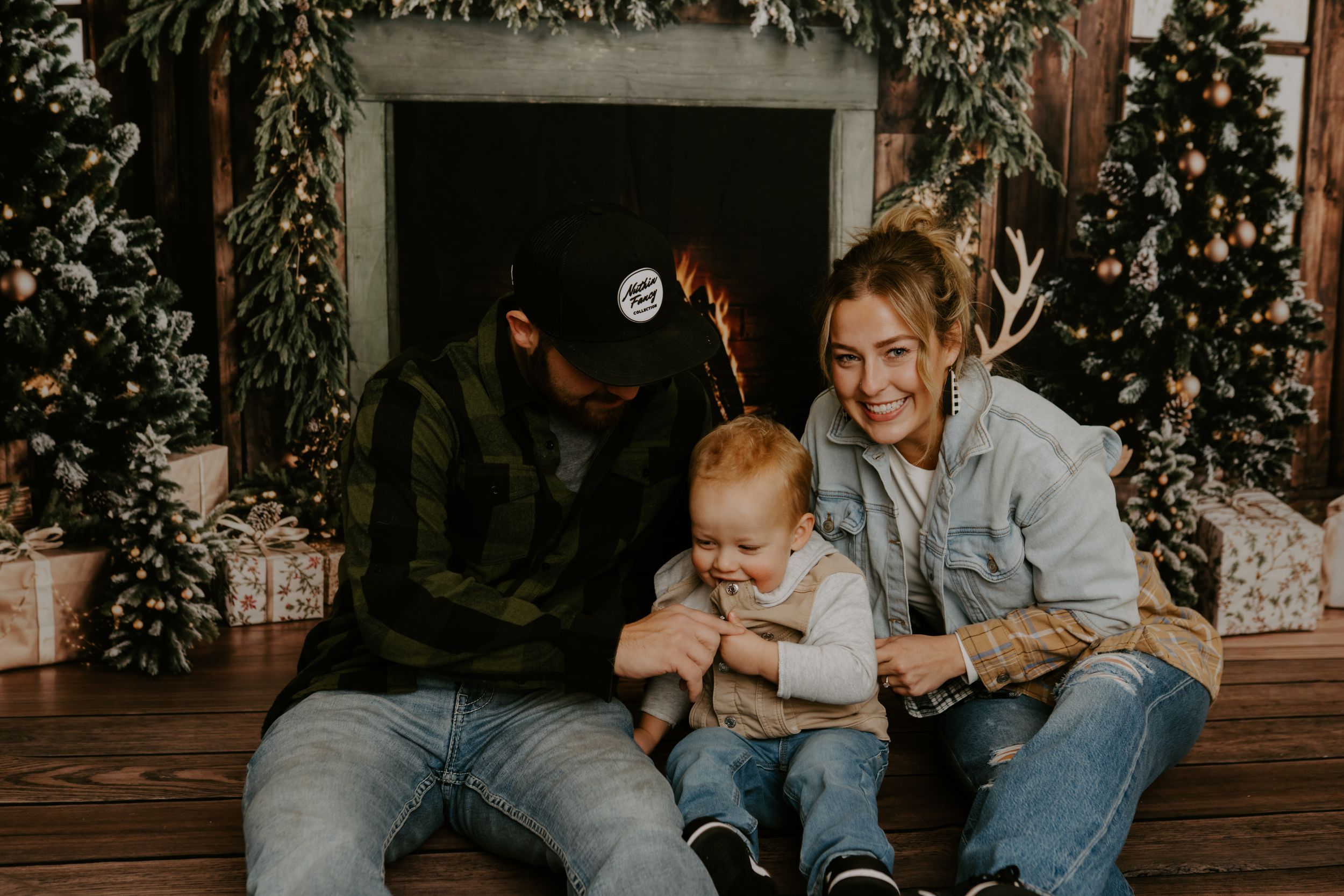 Family holiday portrait session with decorated Christmas trees in background.