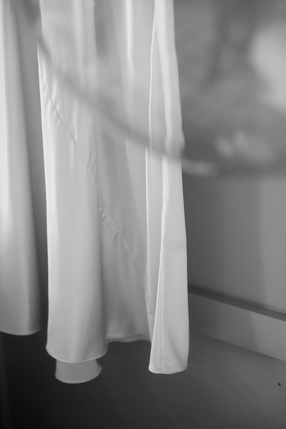 A black and white artistic photograph of white curtains hanging in soft light creating a minimalist composition.