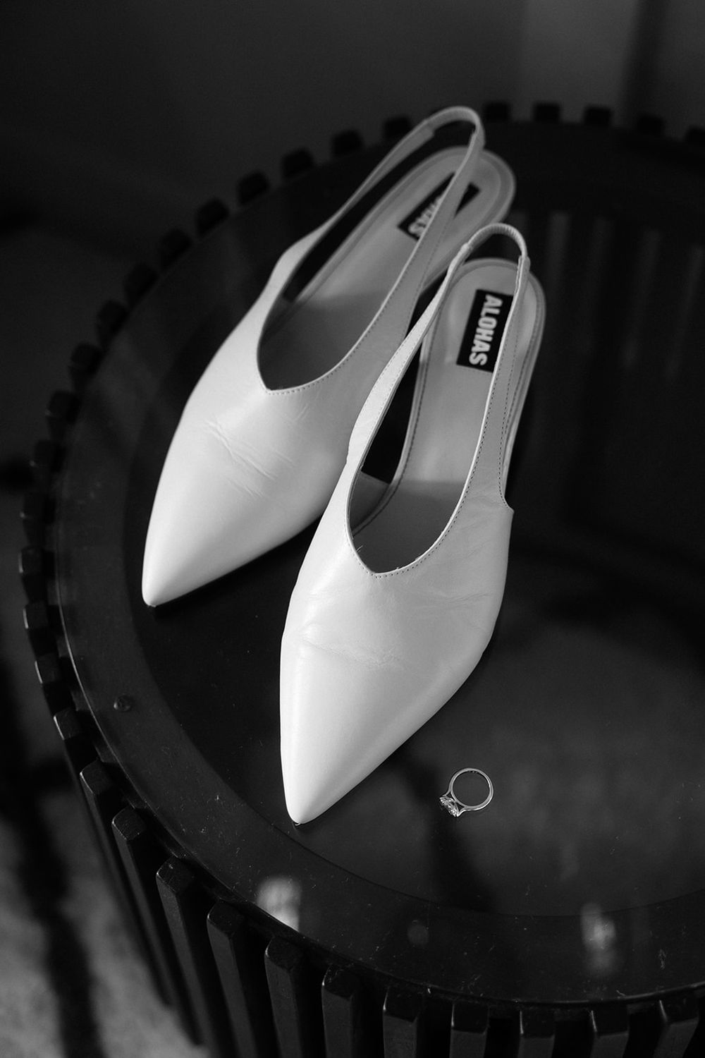 White pointed slingback heels arranged in a repeating pattern against a dark background.