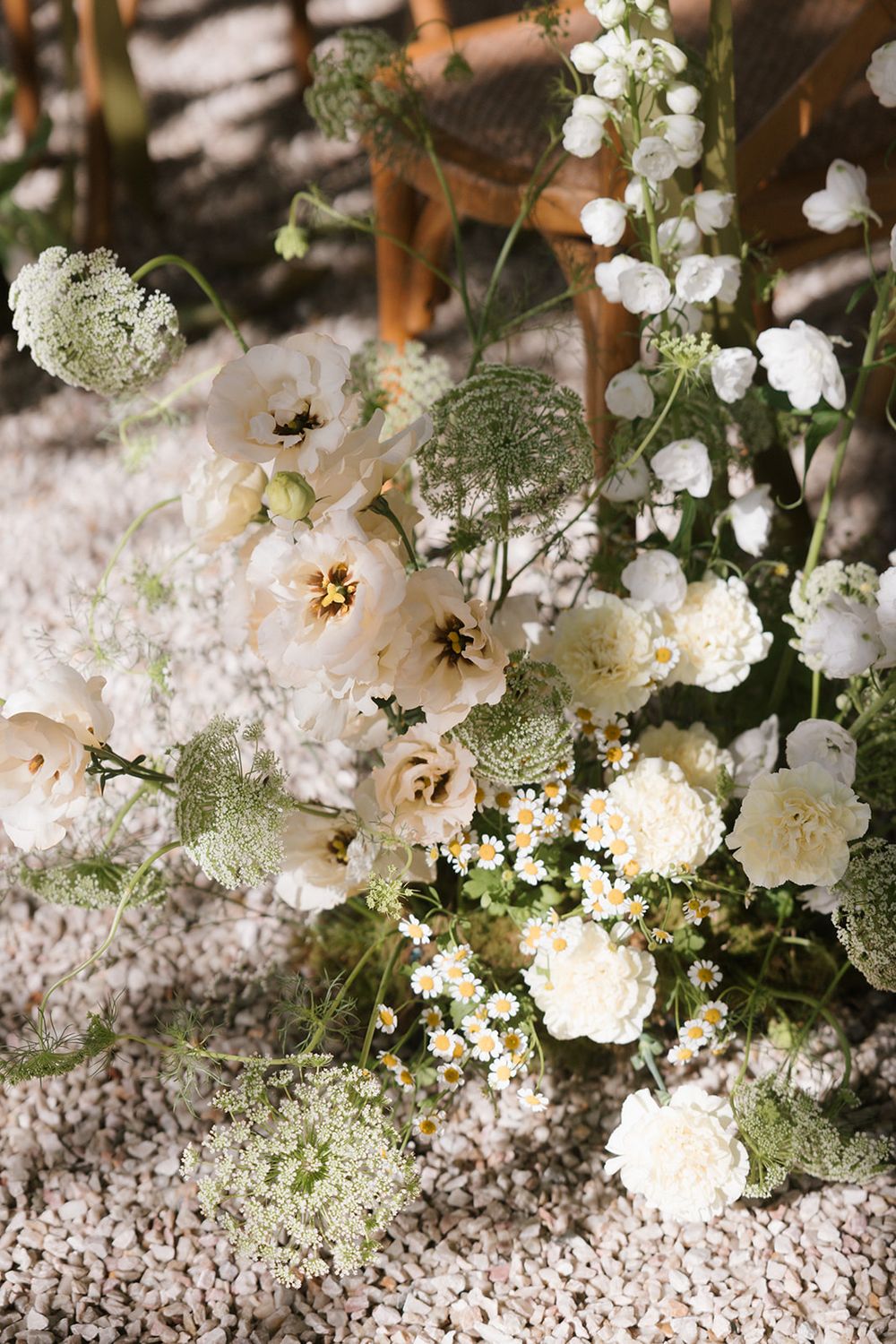 Delicate white hollyhock flowers and baby's breath arranged on a textured stone or concrete surface.
