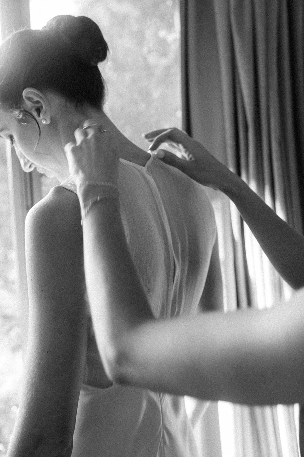 Black and white artistic photograph showing silhouettes of figures getting ready in soft window light.