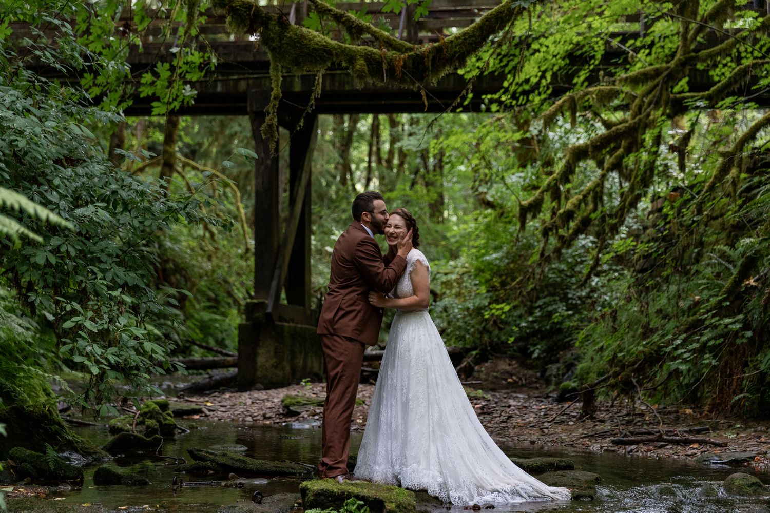 Bride and groom embracing in a creek at Camp Lane after their Ceremony, Pacific Northwest wedding photographer