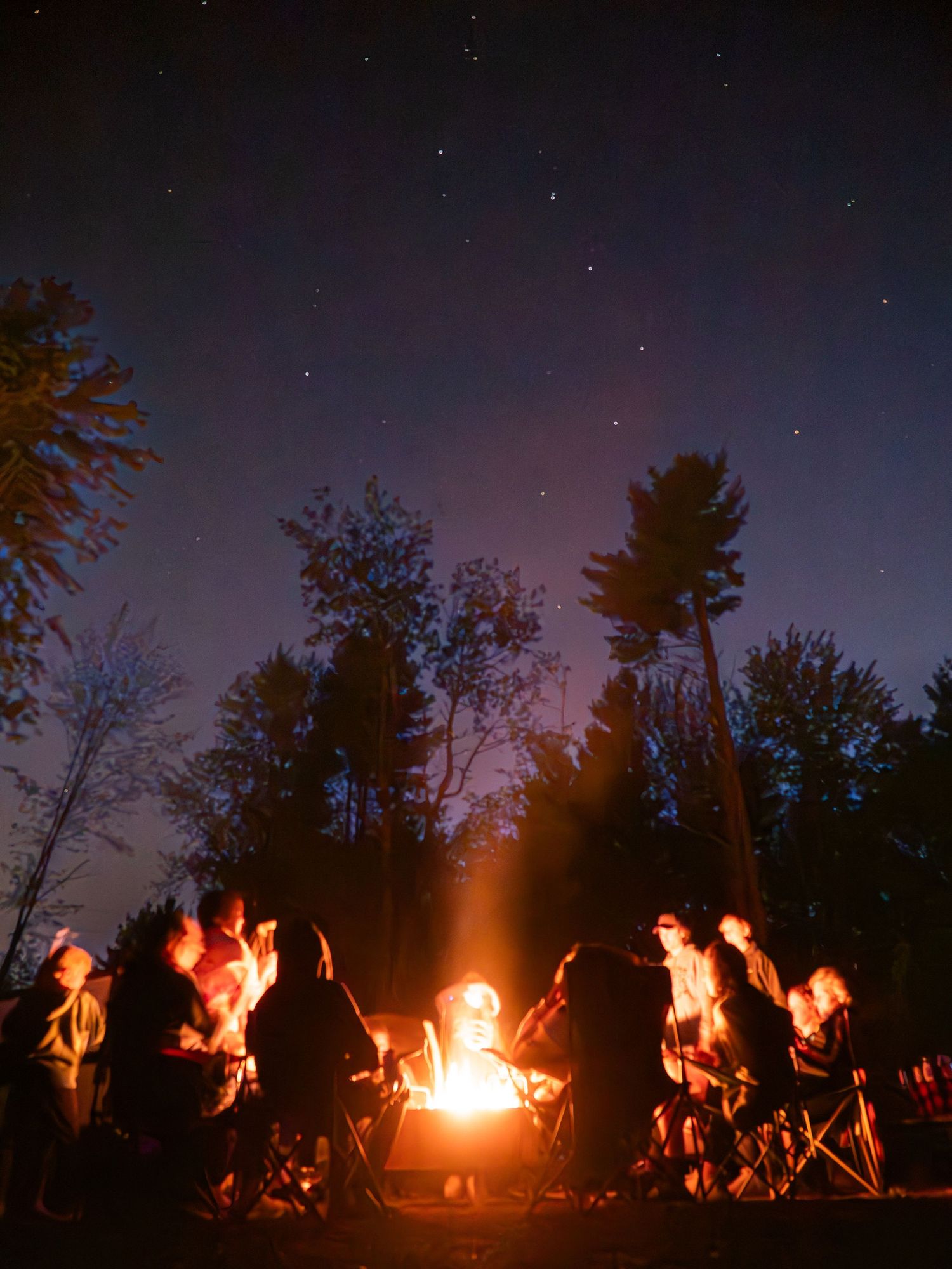 Feu de camp de nuit au Pow Wow d’Odanak, silhouettes autour des flammes dans un cadre forestier