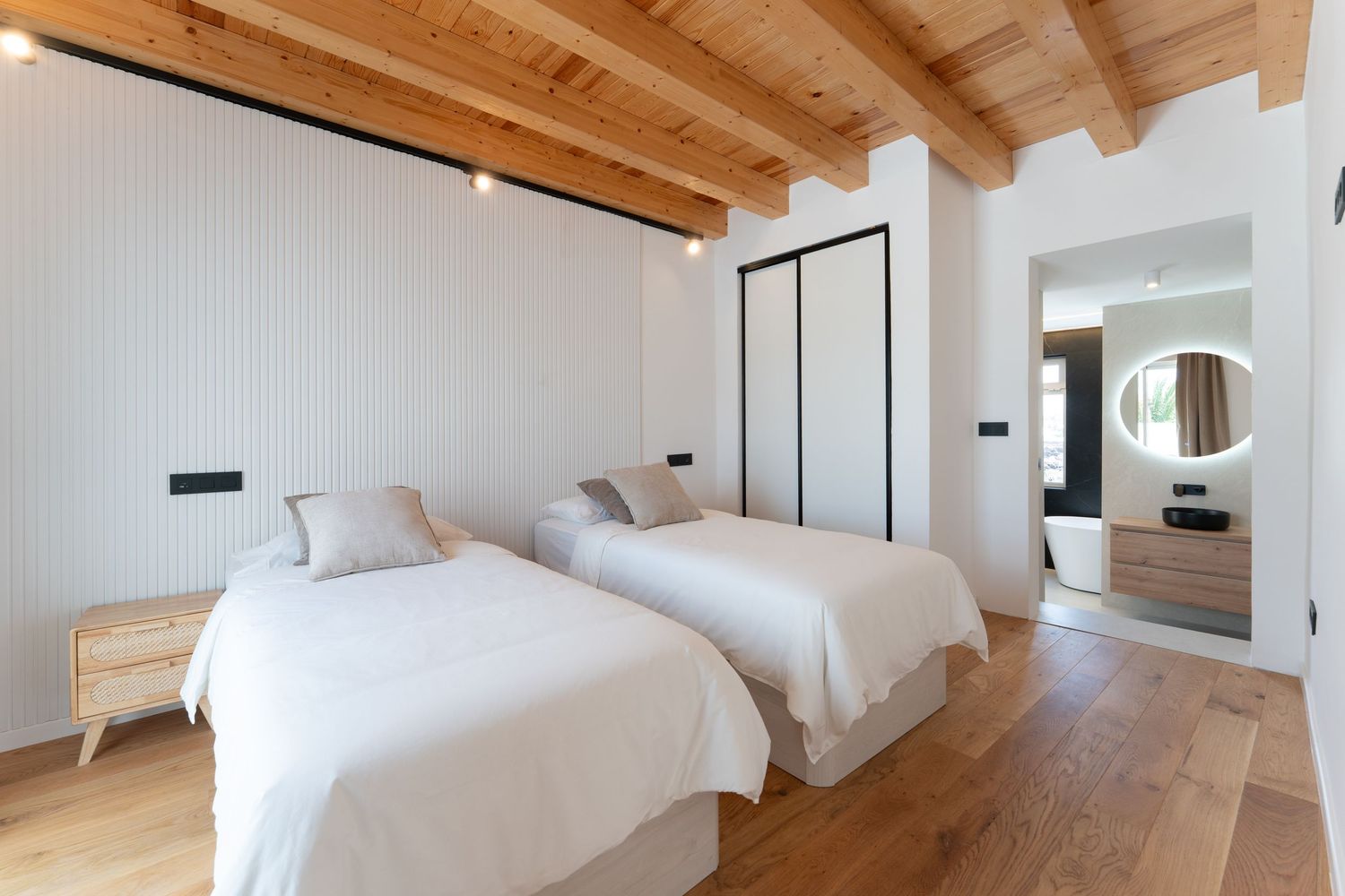Modern minimalist apartment interior with white walls, grey furniture, and natural light flowing through large windows.