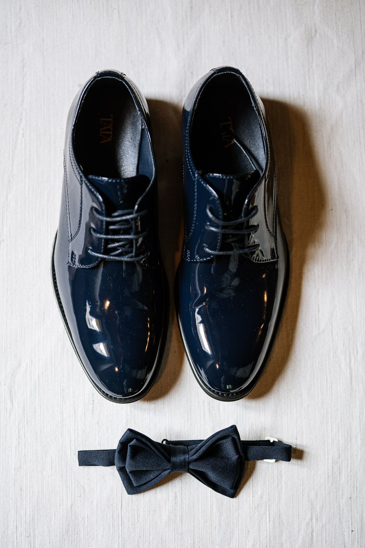 A series of shiny navy blue dress shoes arranged in different positions on a white background.