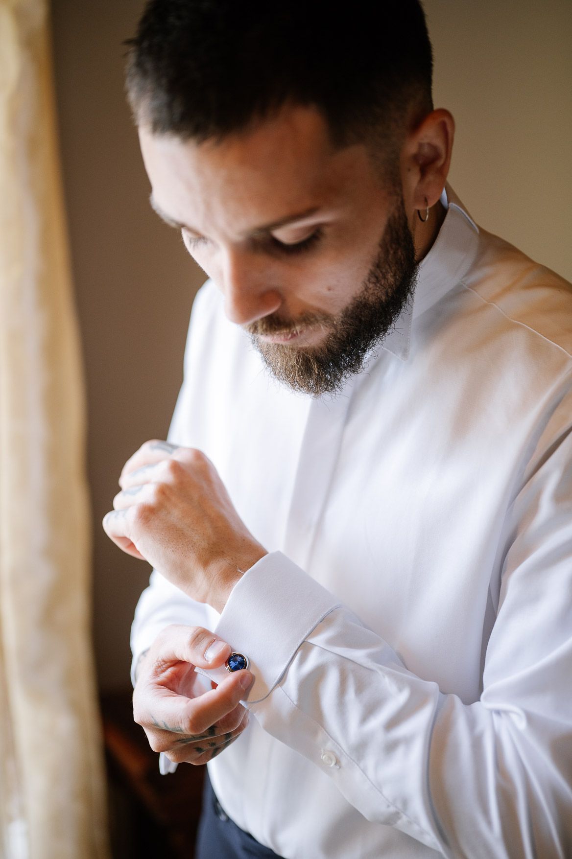 Close-up view of someone in a white dress shirt wiping their nose with a tissue.
