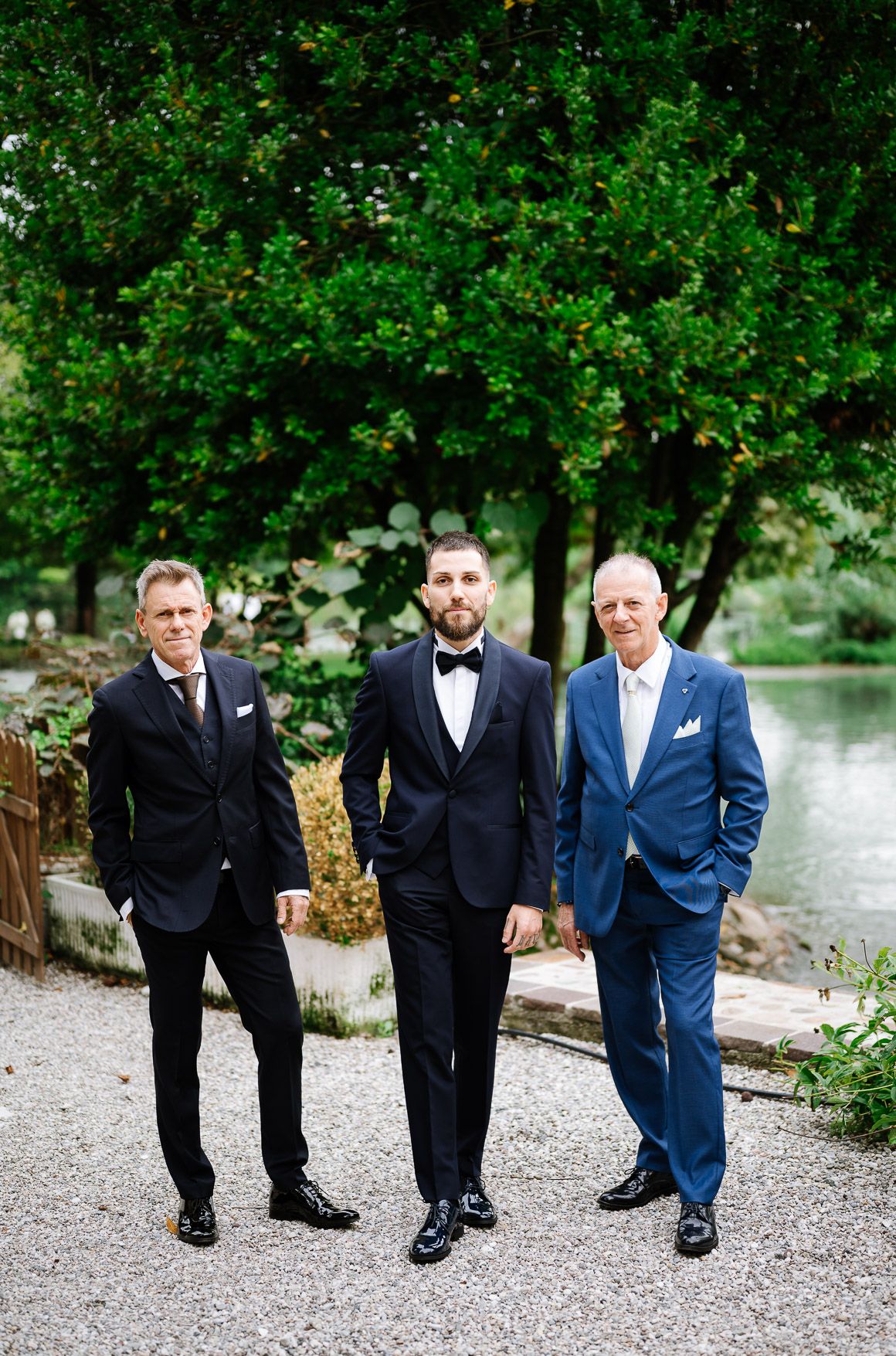 Wedding party walking and posing on a gravel path surrounded by lush green trees and foliage.