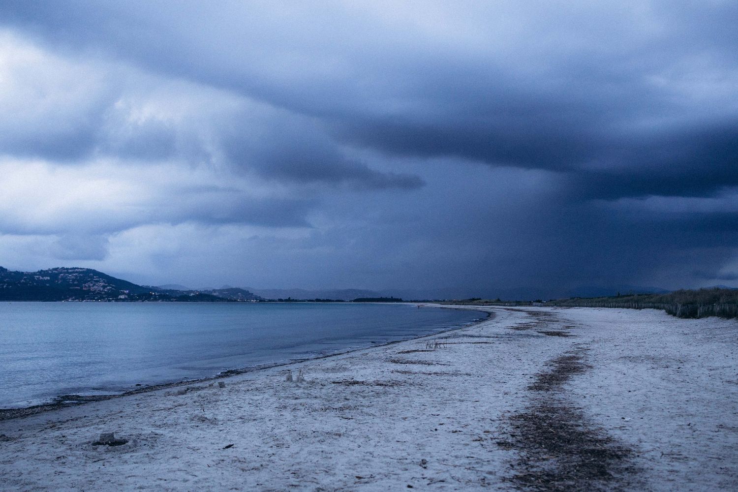 A series of panoramic beach photos showing stormy skies and dramatic weather conditions over coastal waters.