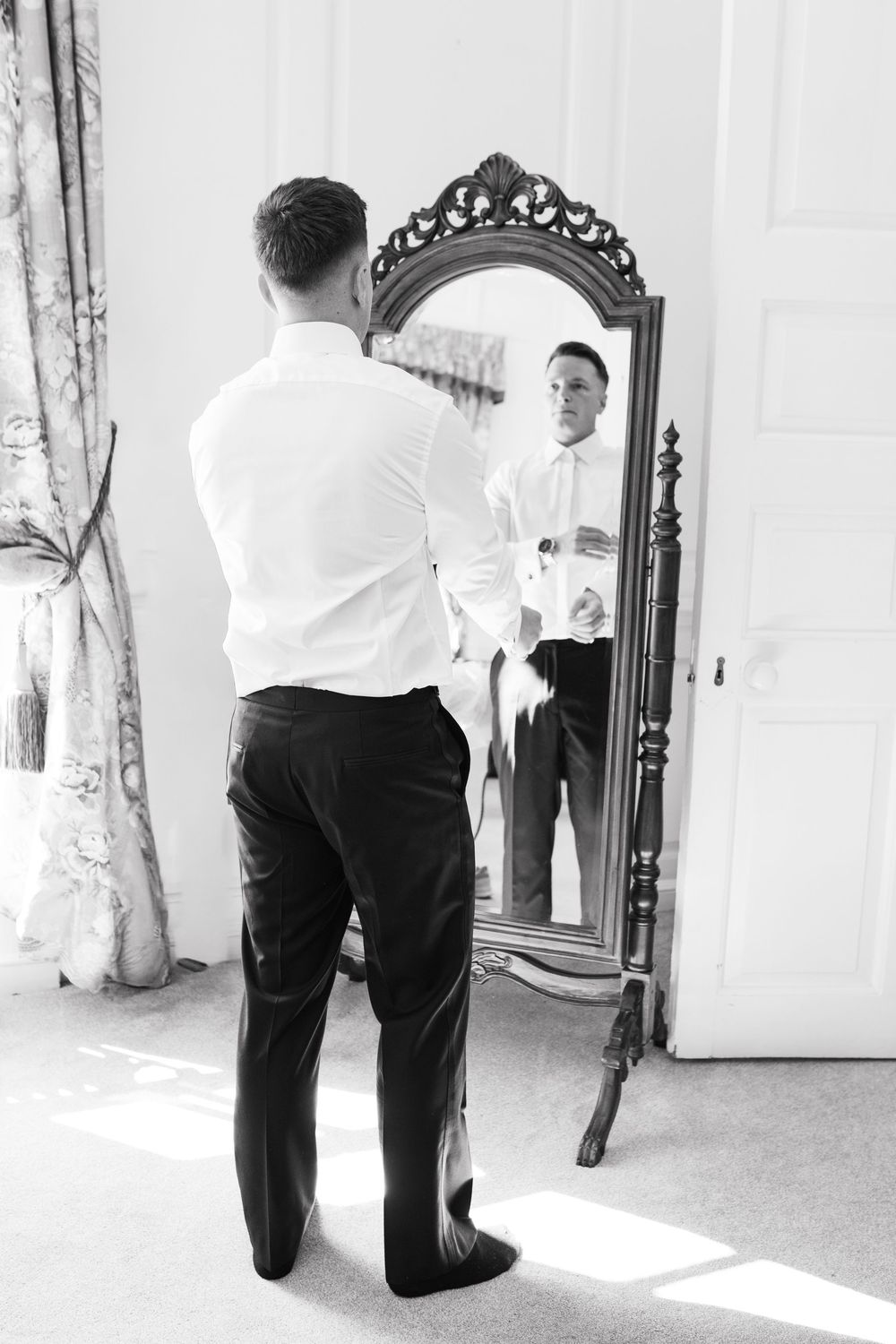 A black and white photo series showing a person kneeling and proposing in an elegant hallway setting.