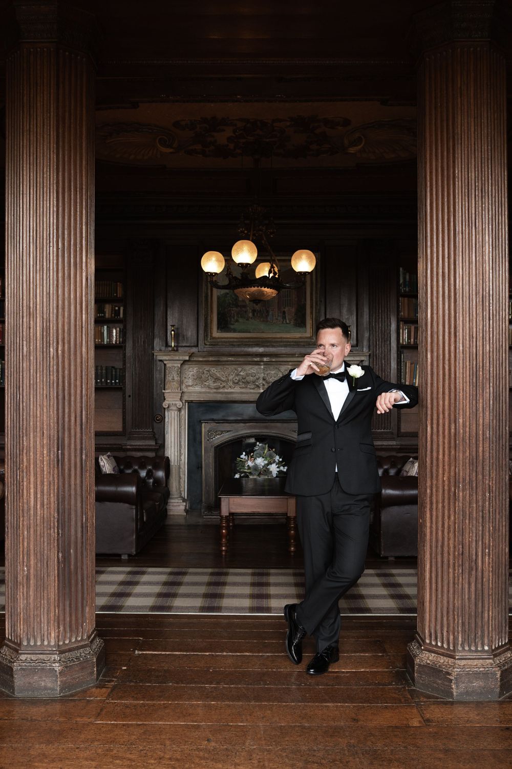 A person in a tuxedo performs a dramatic dance sequence across a grand hall with wooden columns and vintage lighting.