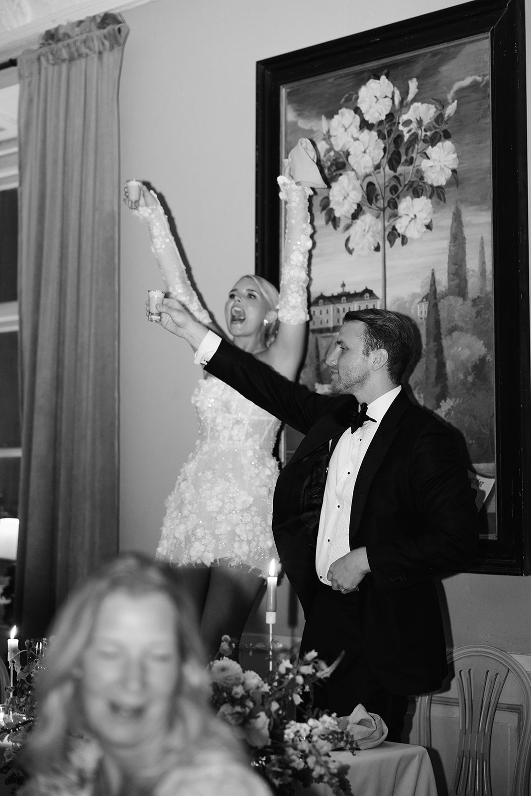 Black and white photo series showing a couple celebrating joyfully at what appears to be a wedding reception.