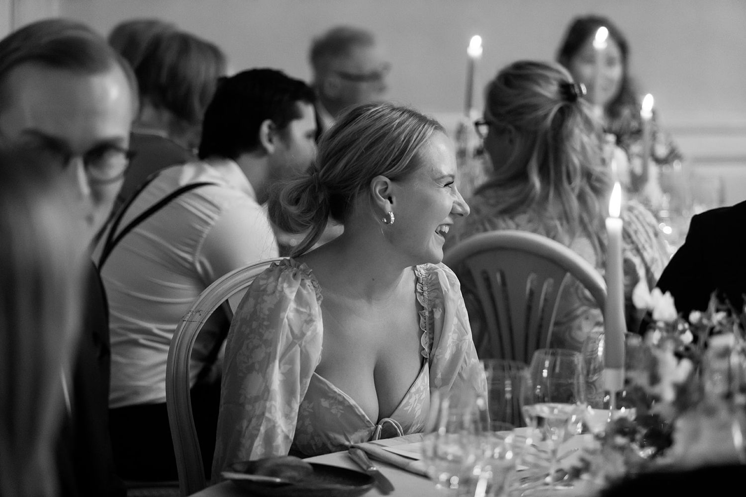 Black and white photo showing people seated at a wedding reception table during a celebration.