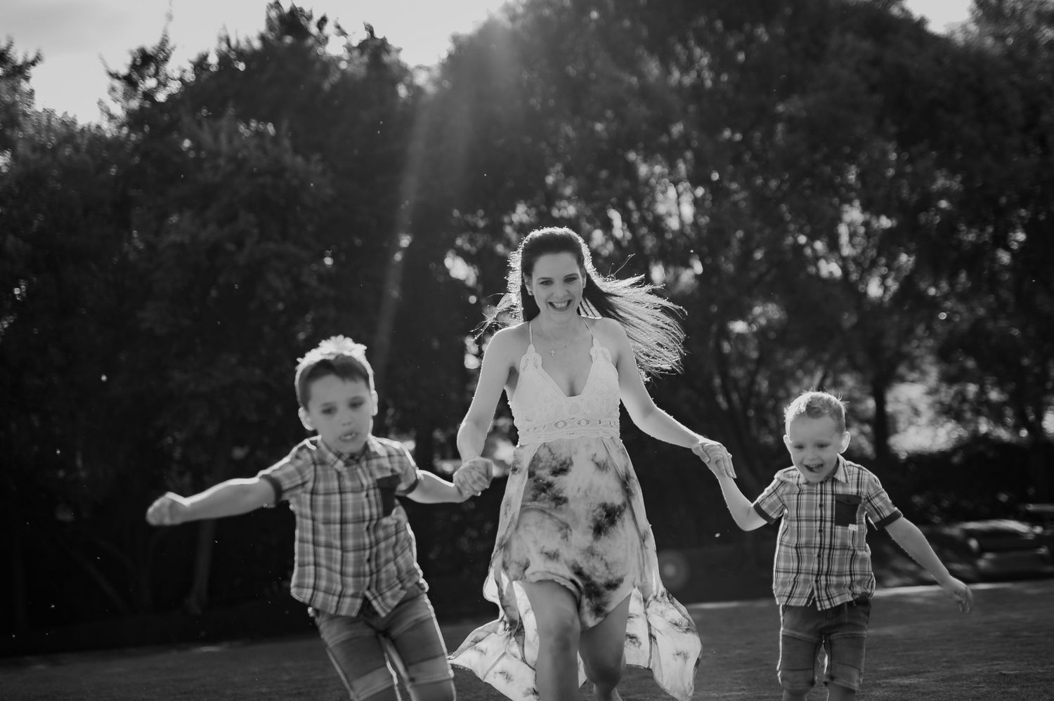 A series of black and white candid photos showing playful moments between people outdoors in natural light.
