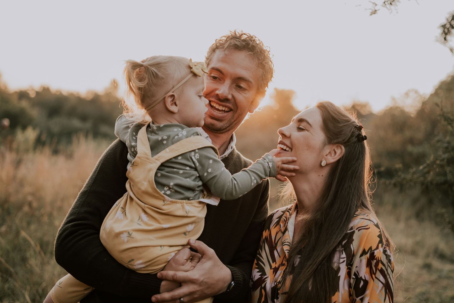 Family shares joyful moments together during golden hour photoshoot in a rustic outdoor setting.