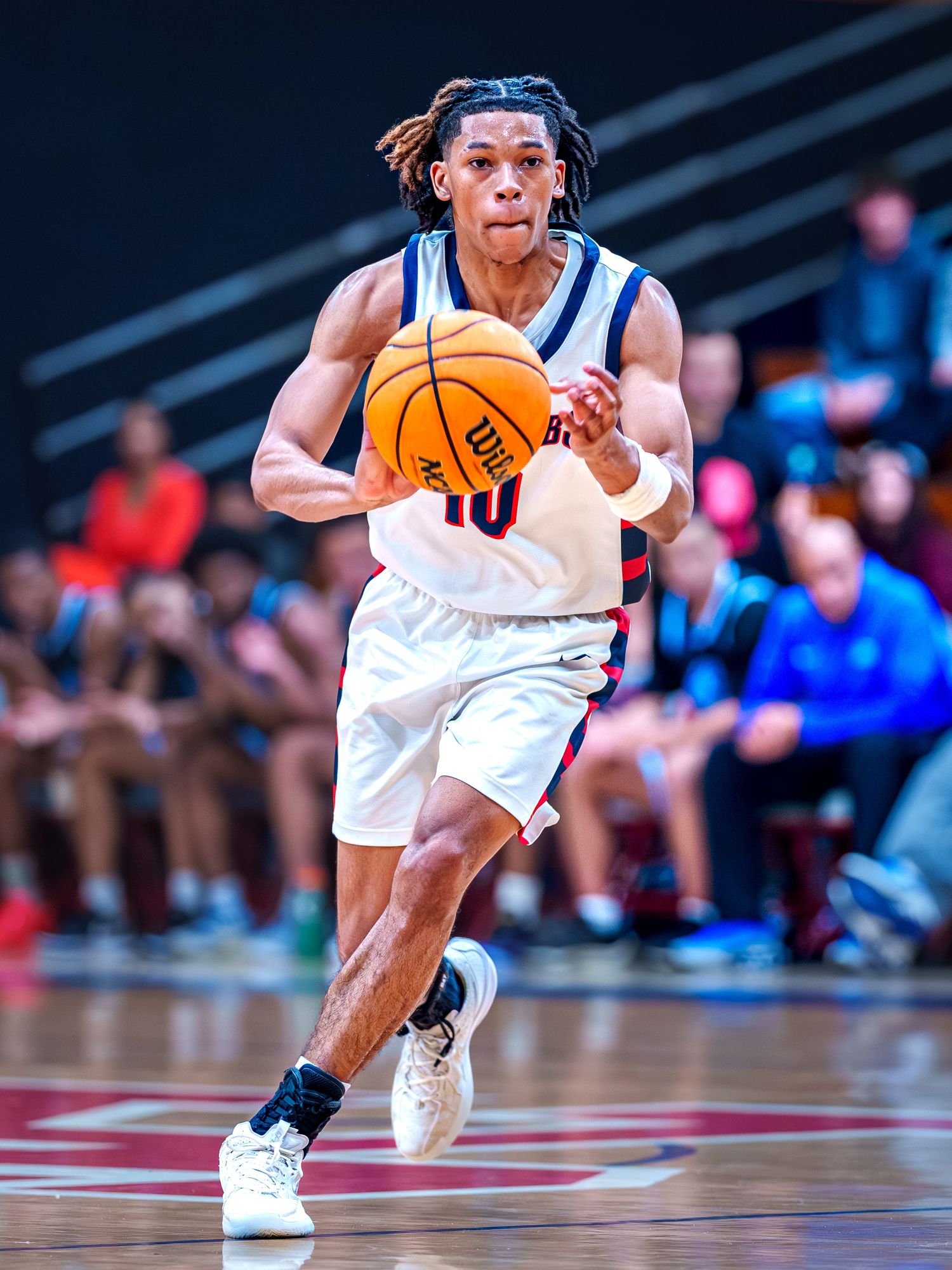 NBA basketball player in white uniform dribbles ball during intense game action on professional court.
