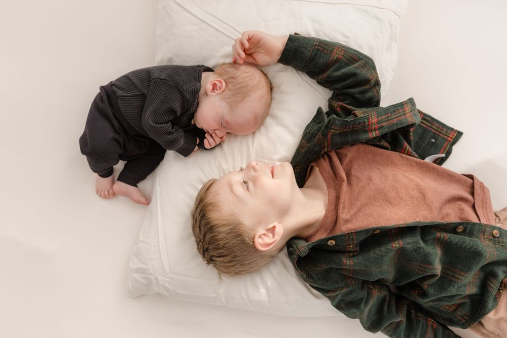 Series of monochromatic photos showing a sleeping baby in different poses on a white backdrop.