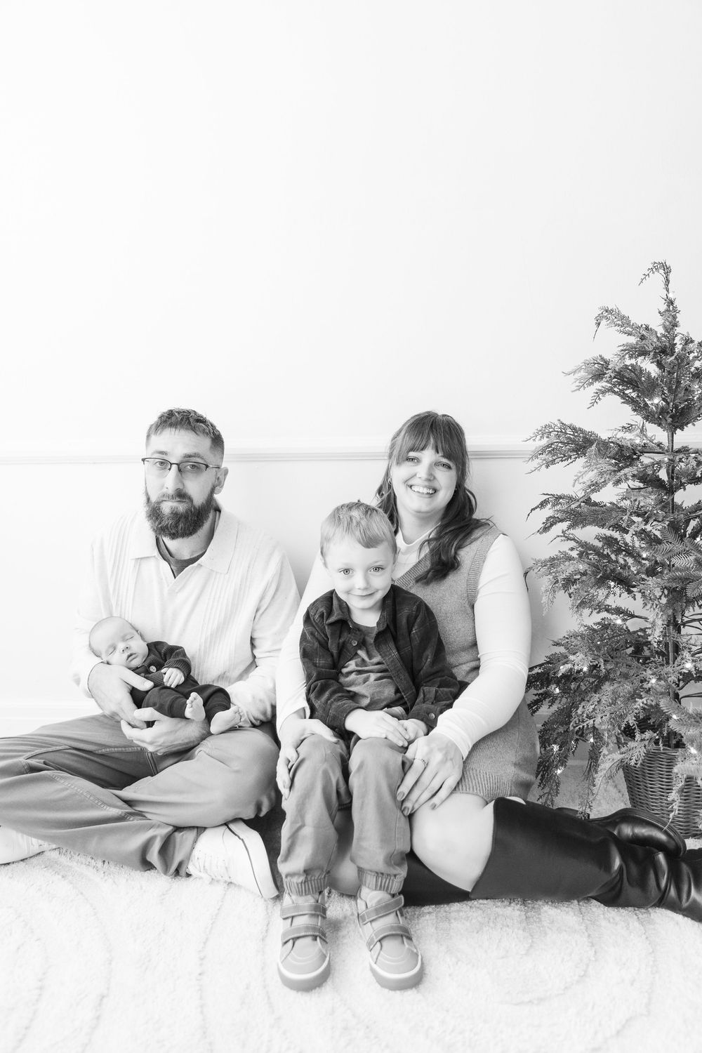 A black and white photo series showing a family relaxing together on a couch with a Christmas tree in the background.
