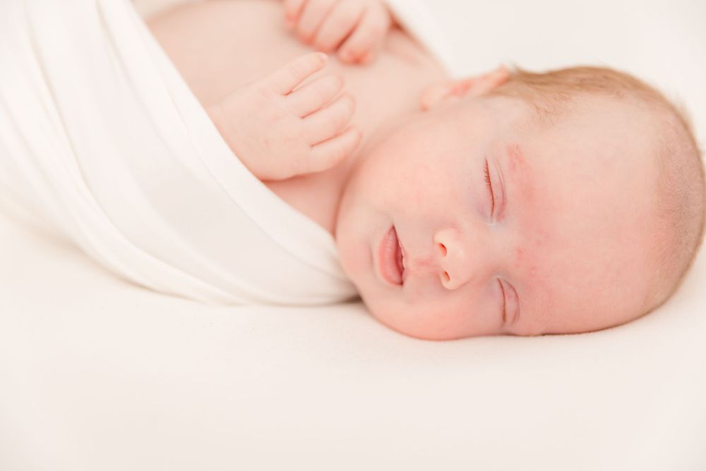 Serene newborn portrait with delicate details in high key lighting.