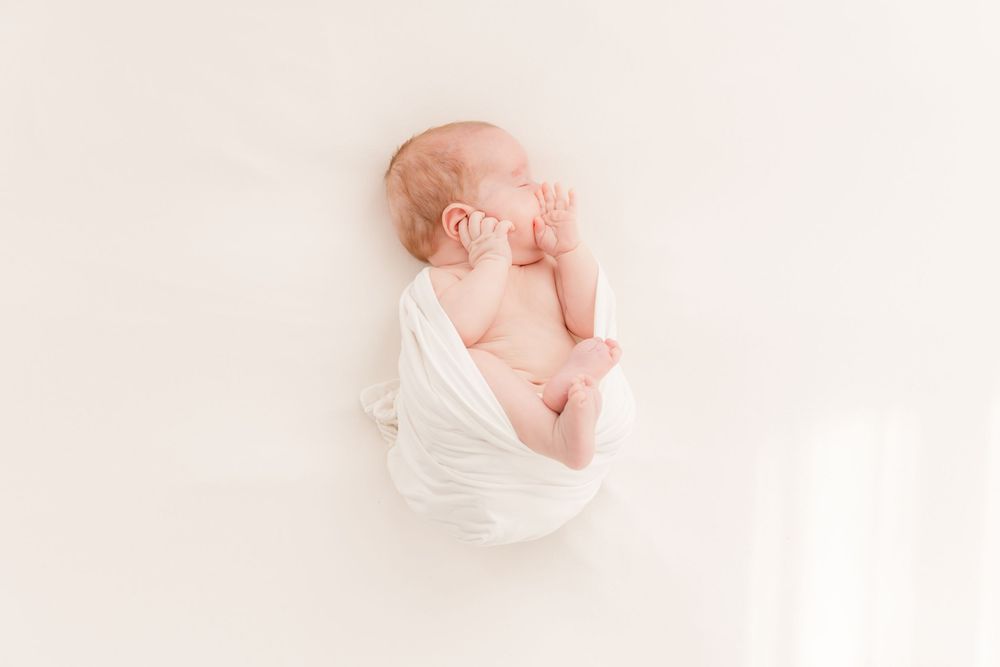 Minimalist black and white newborn photography with gentle wrapping.