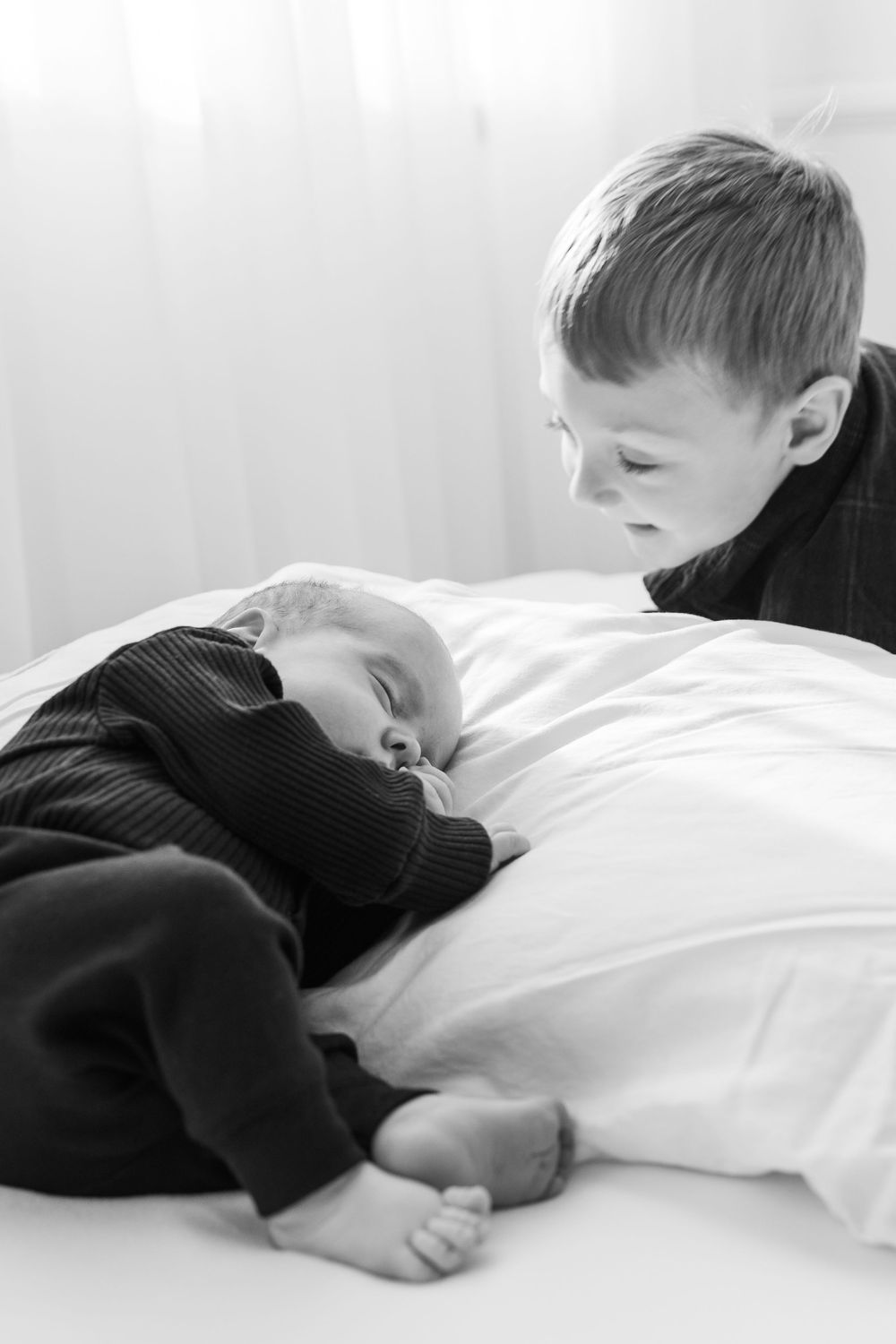 A sequence of black and white photos showing a sleeping child in a dark sweater on white bedding.