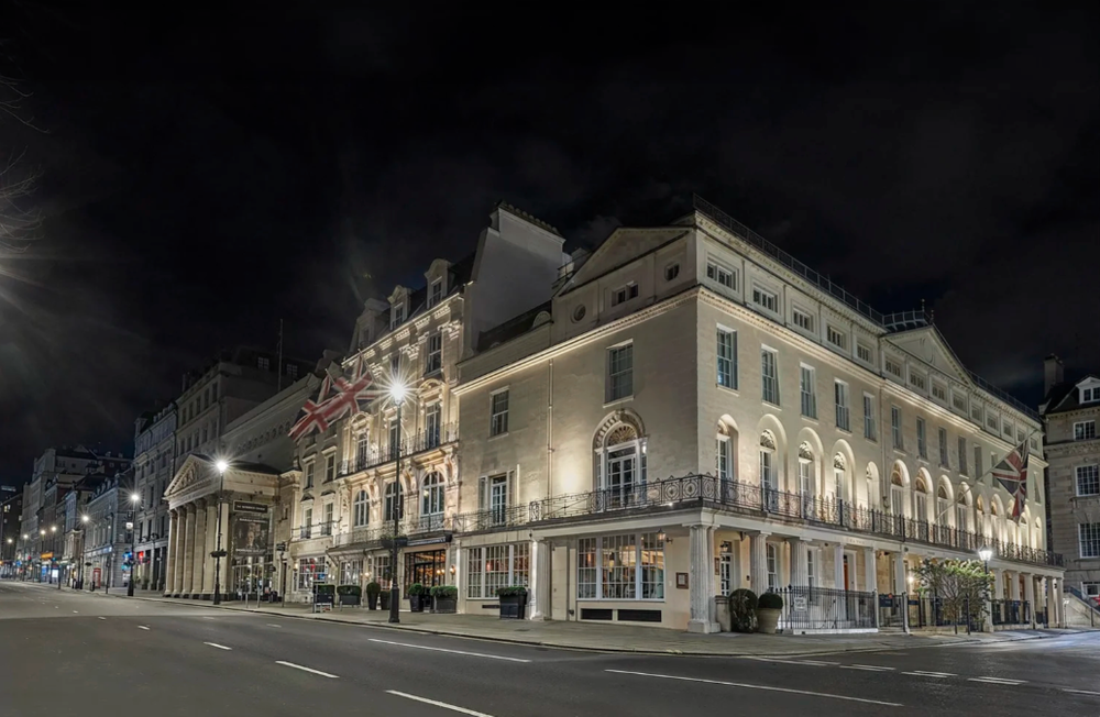 Panoramic nighttime view of illuminated historic buildings along a quiet street.