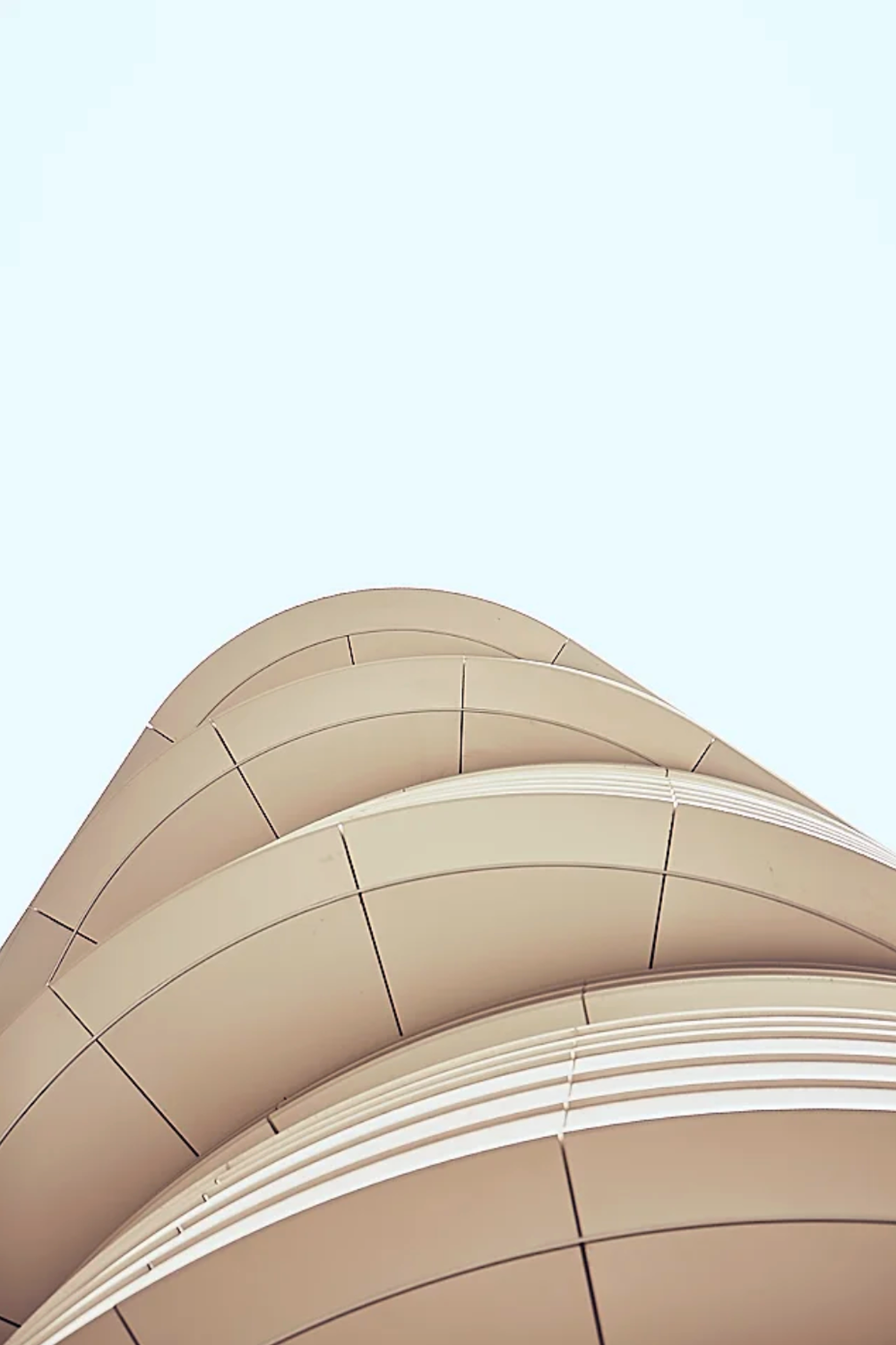 Abstract curved architectural detail in beige tones against white background.