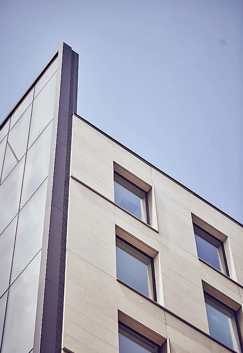 Contemporary building facade with angular white walls and rectangular windows.