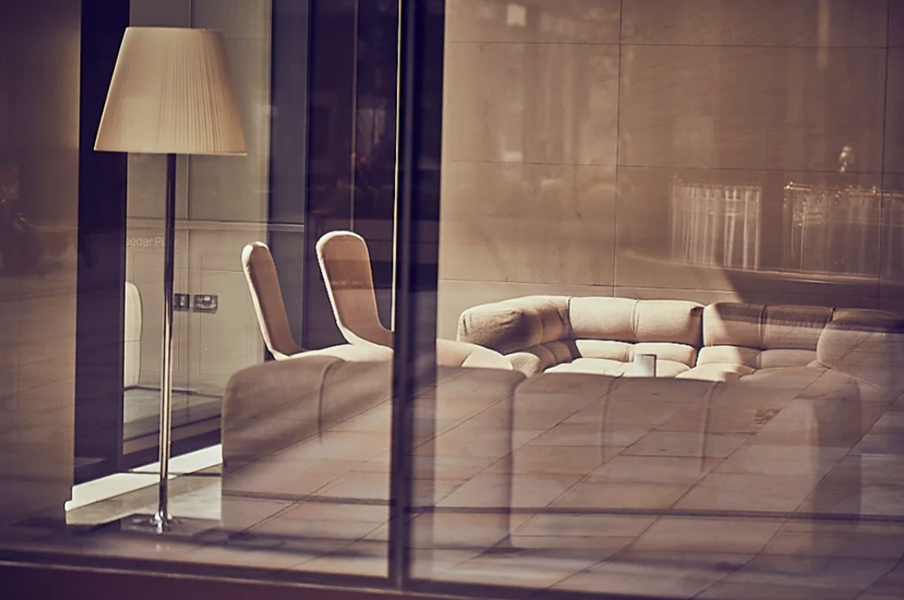 Interior view of modern space with lamp and furniture through glass windows.