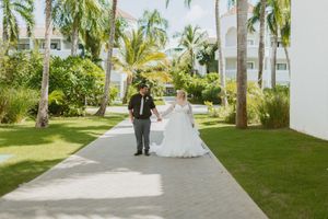 Palm tree-lined walkway at a tropical resort with white buildings and manicured grounds.