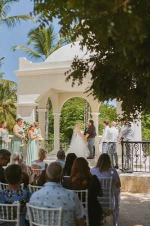 Outdoor wedding ceremony setup with white chairs and Mediterranean architecture overlooking the water.