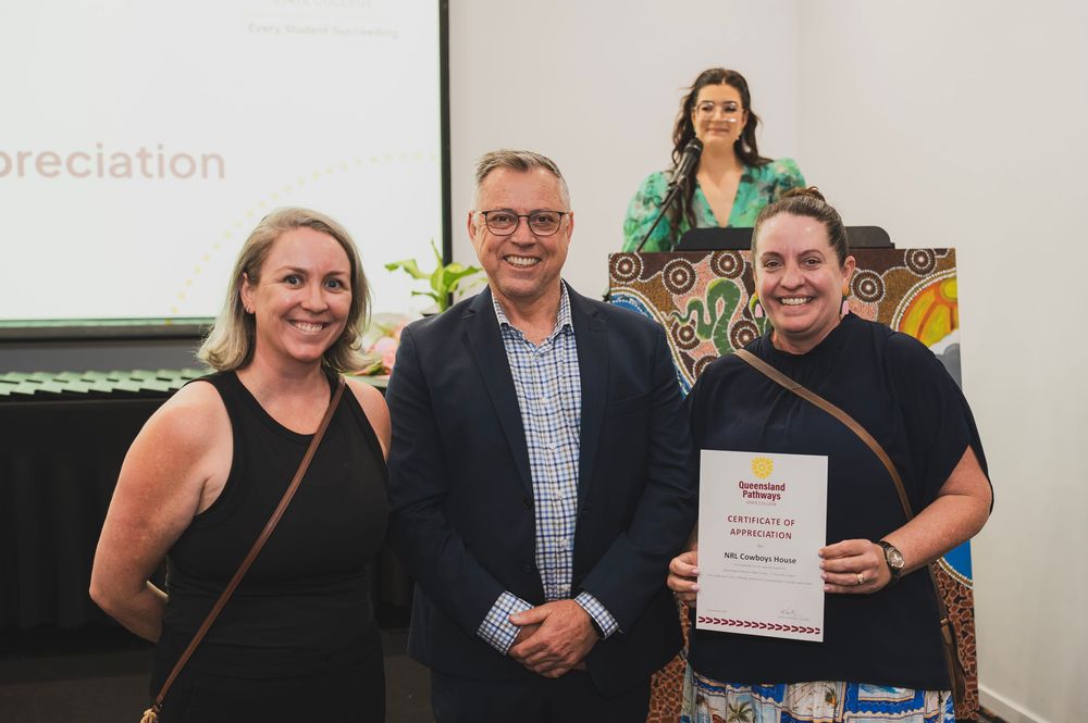 A group of people stand together smiling while holding award certificates at a recognition ceremony.