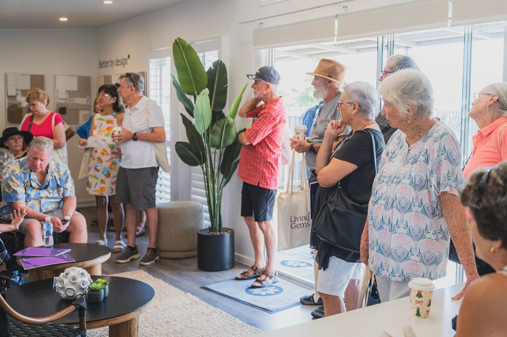 A group of people gathered in a bright modern space with large windows and indoor plants.