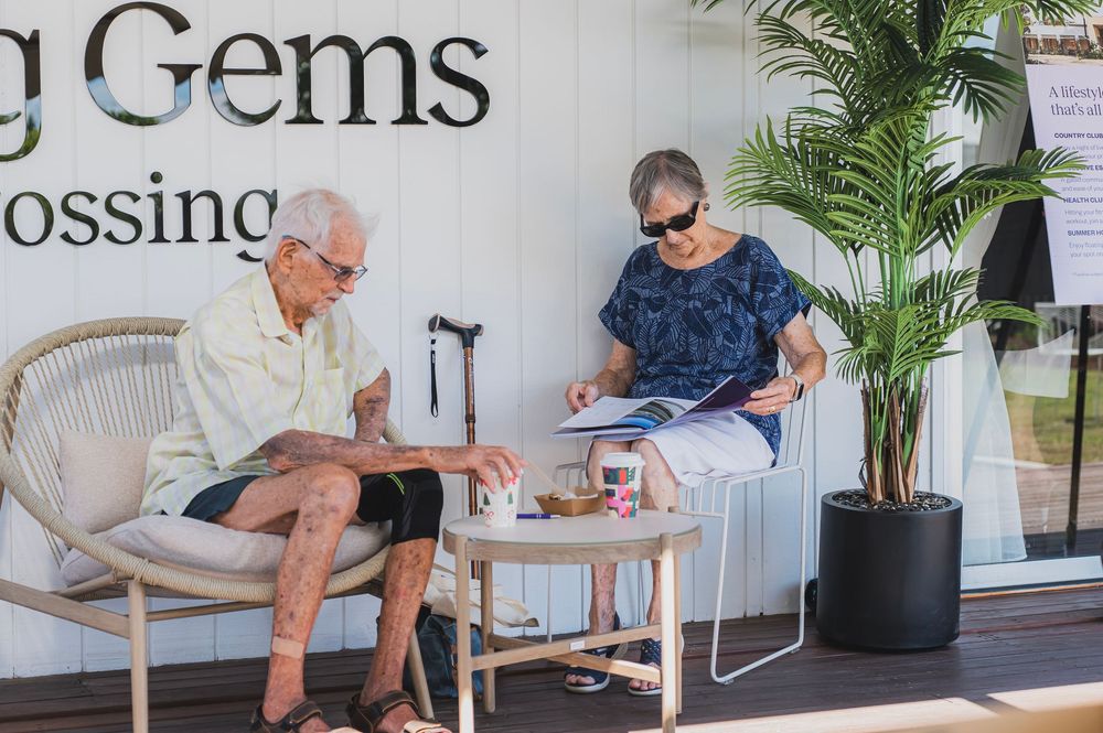 A row of people relaxing in cushioned chairs at an outdoor patio or lounge area.