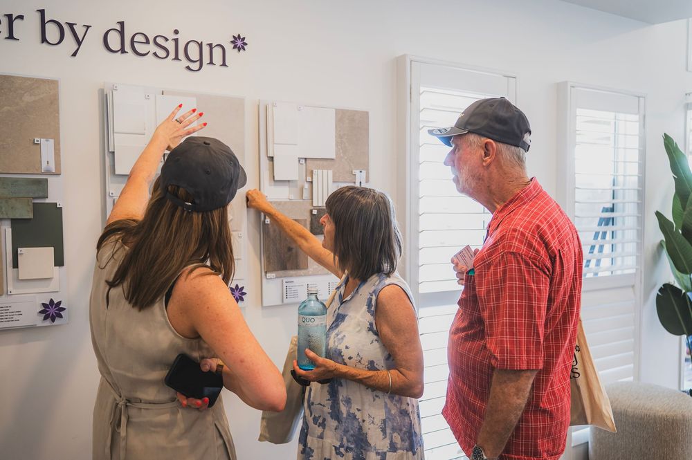 Group of people examining and discussing interior design elements in a modern white office space.