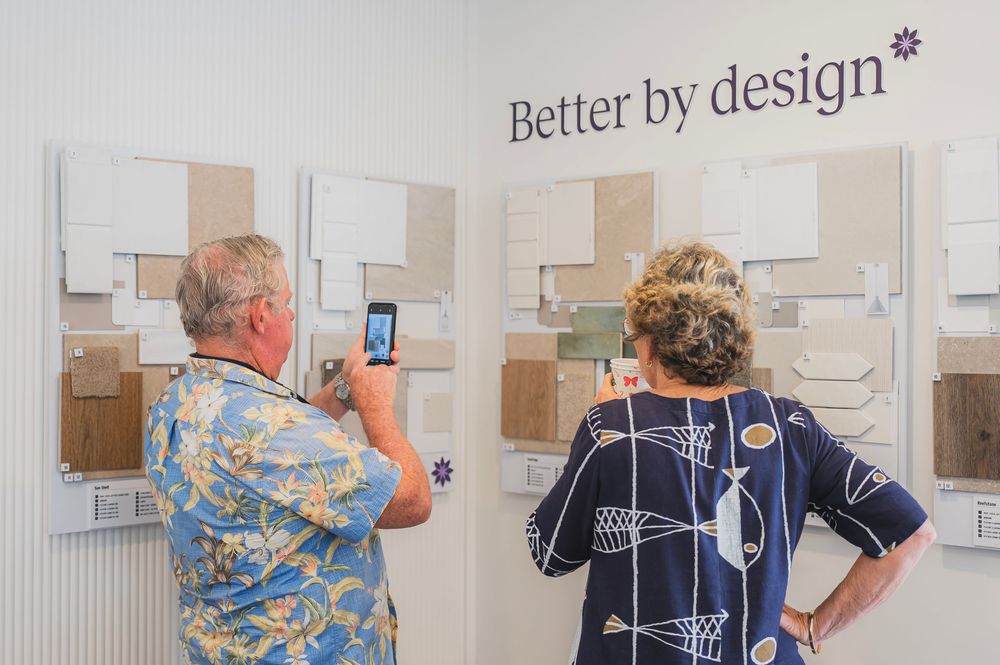 Two people looking at design samples on a wall under a Better by Design sign.
