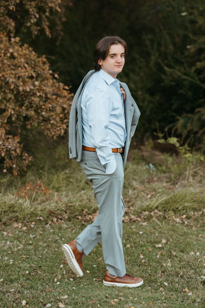 Modern business casual look with grey suit and sneakers captured in an autumn outdoor setting.