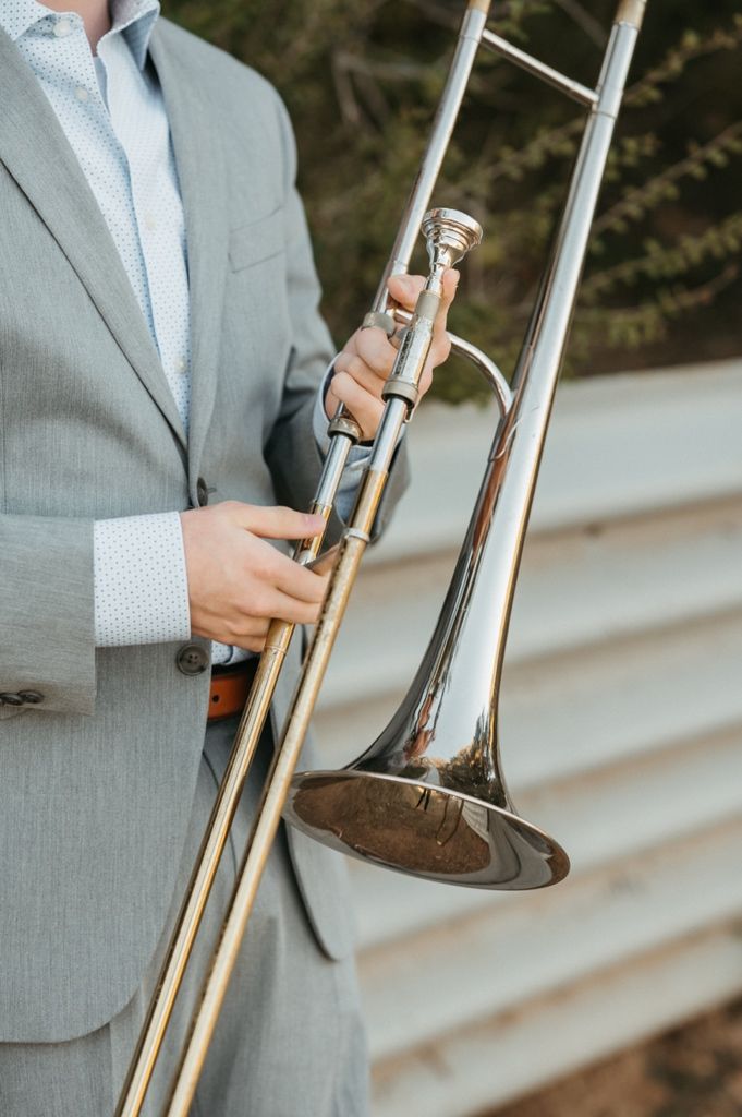Close-up shots of hands holding a brass trombone against a light background with concrete steps.