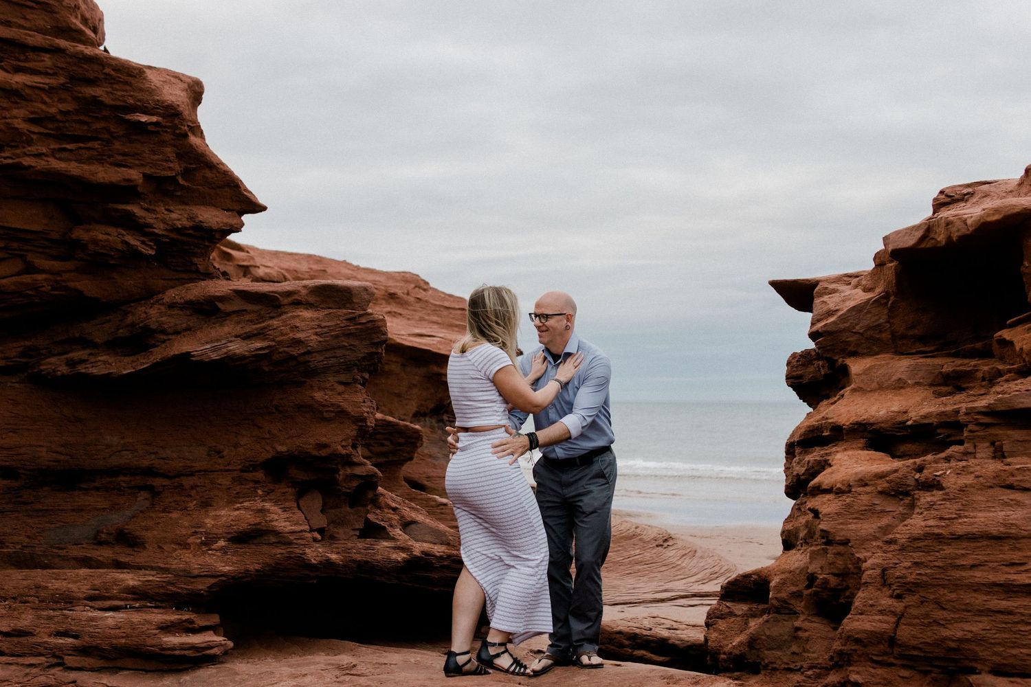 A couple stands together on red rock formations during their elopement photoshoot at sunset in Utah.