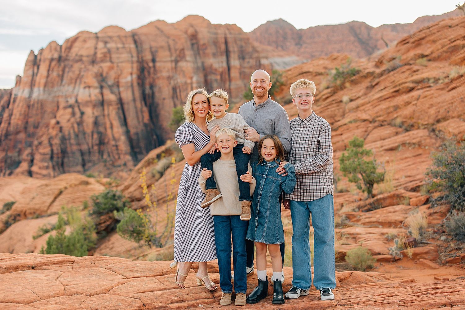 Family portraits captured against stunning red rock formations in desert landscape.